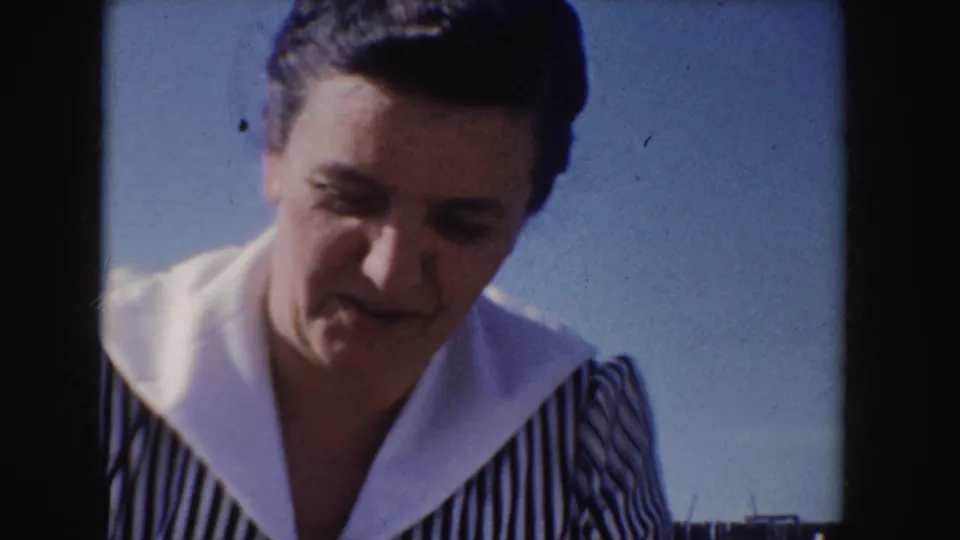 Close-up of an adult woman in Idaho, 1955, looking down in sunlight while wearing a striped dress with a broad white collar.