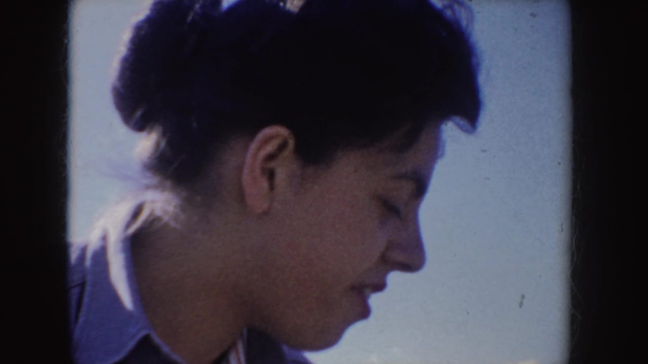 Woman in profile beside a man holding a cup against a bright sky.