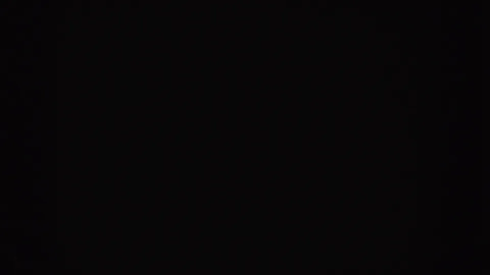 1955 Idaho 8mm frame begins in near darkness, with minimal visible detail beyond black shadow and film grain.