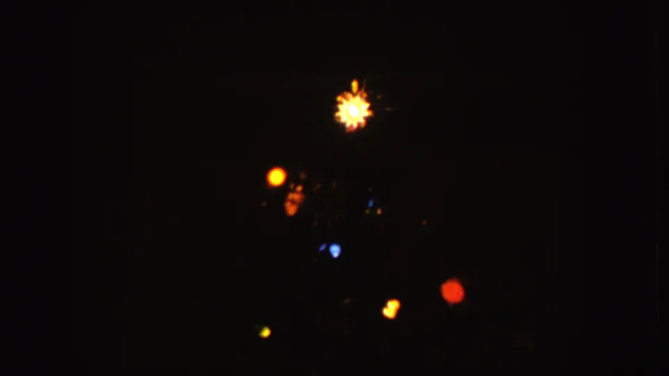 1955 Idaho 8mm frame showing soft yellow, red, blue, green, and orange lights against darkness.
