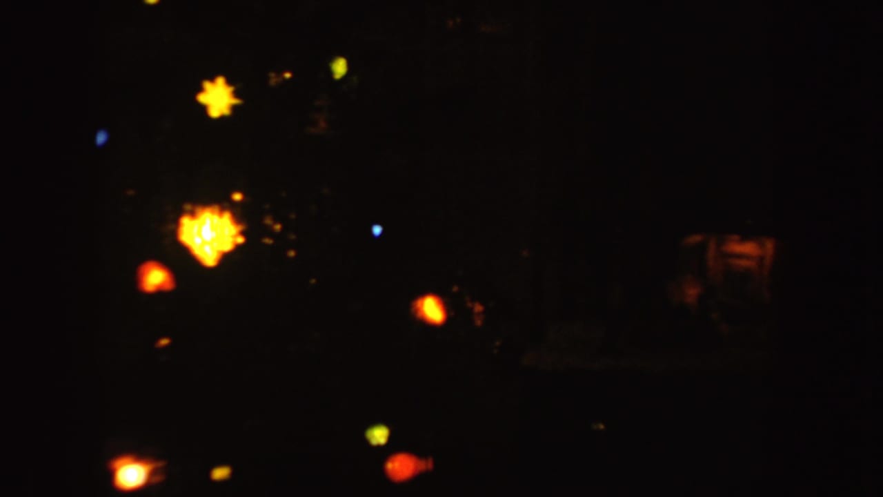 1955 Idaho 8mm frame with warm colored Christmas lights glowing softly in a very dark interior.