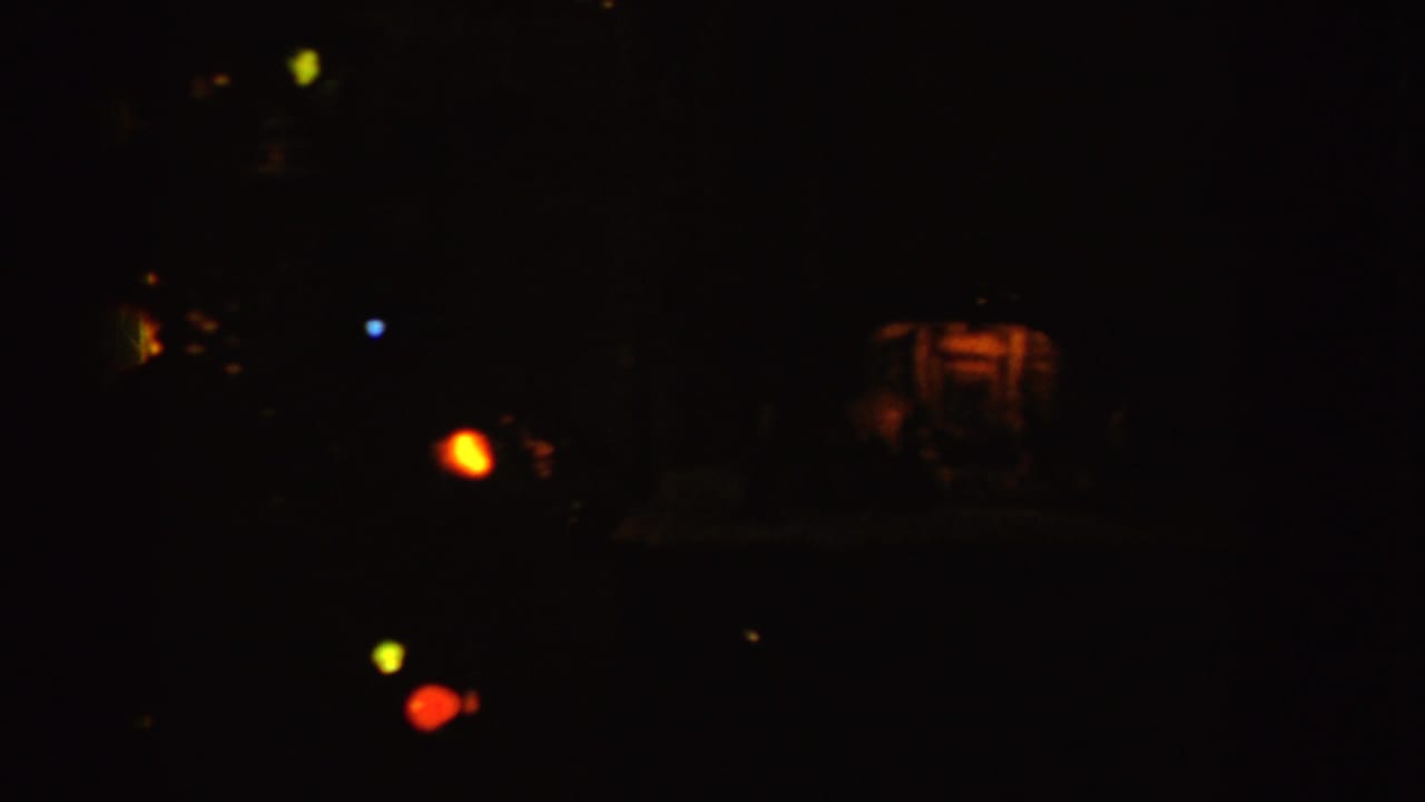 Dark interior with faint furniture and scattered holiday lights.