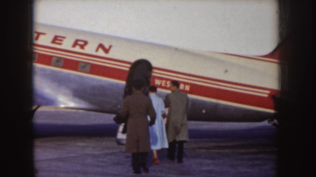 Passengers in coats gather near the open door of a Western Airlines aircraft on an Idaho tarmac in the supplied 1955 metadata context.