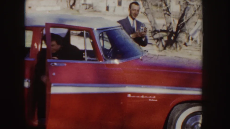 The red station wagon is shown closer, with a man standing by the open door and a seated person visible through the side window.