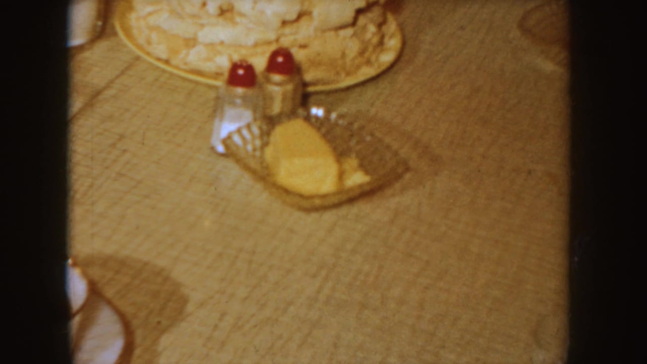 Breakfast table with plate of food, butter dish, and red-topped salt and pepper shakers.