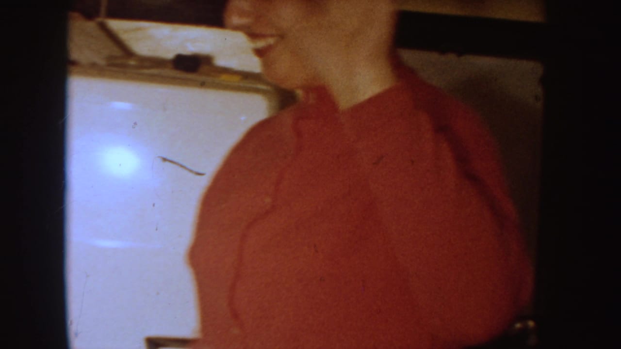Partly visible person in a red top beside a pale kitchen or dining surface.