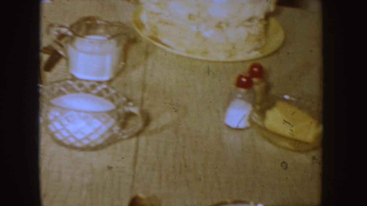Dining table set with cake, milk pitcher, salt shaker and butter dish.