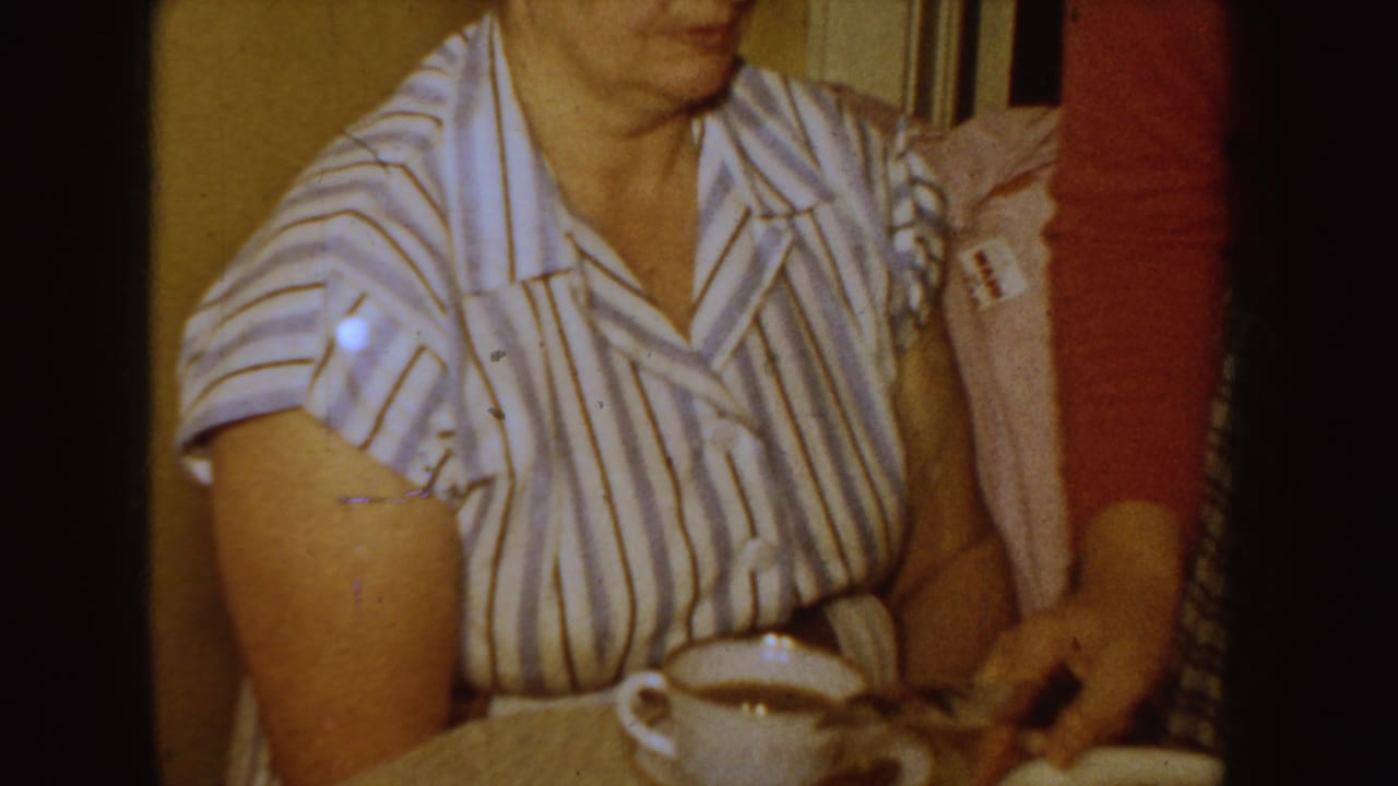 Woman in striped blouse seated indoors with a coffee cup on a table.