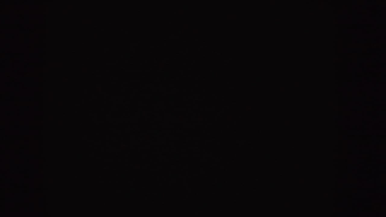 Dark blank frame with slight grain and faint blue-toned marks.