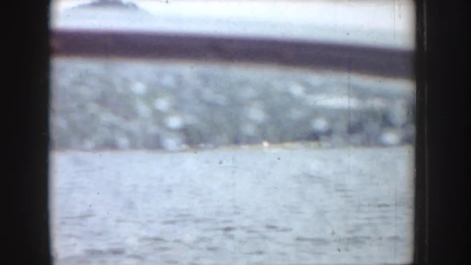 1955 Idaho 8mm frame with a bright rectangular opening, dark surrounding edges, and an indistinct pale outdoor view.