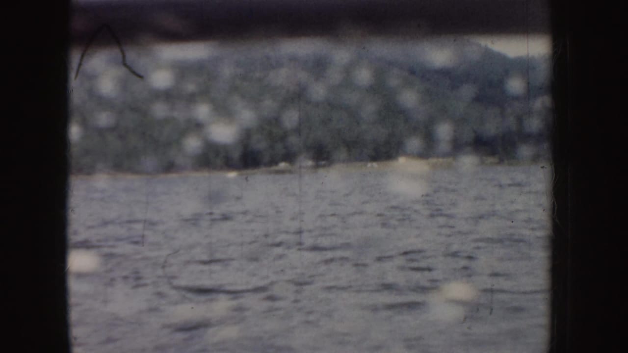 Rippled water and forested mountains behind a dark rail frame.