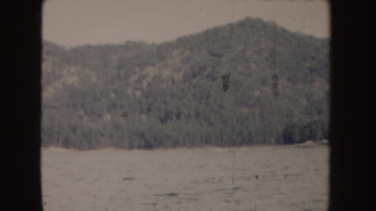 Forested hillside across rippled water with dark 8mm frame borders.