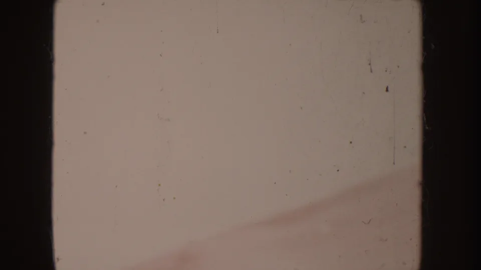 Damaged 1955 Idaho 8mm frame with dark gate edges, visible dust and scratches, and a faint reddish blur near the lower right.