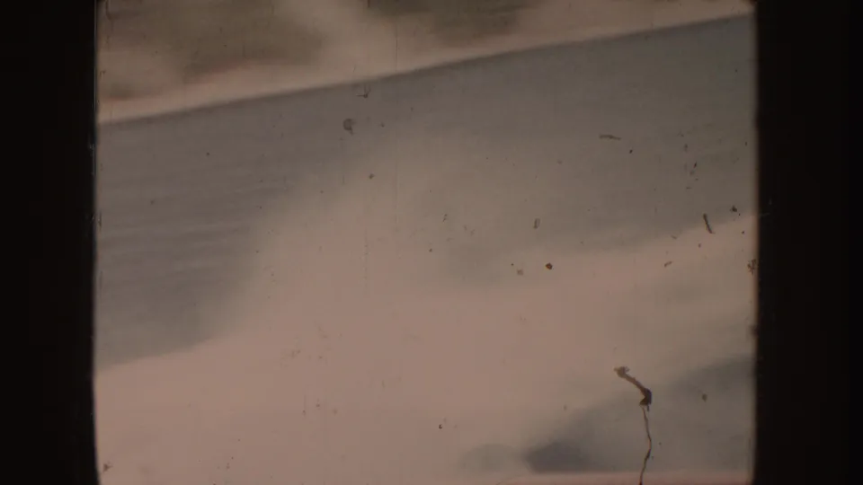 1955-attributed 8mm frame of pale turbulent water, soft motion blur, and heavy film border shadowing.