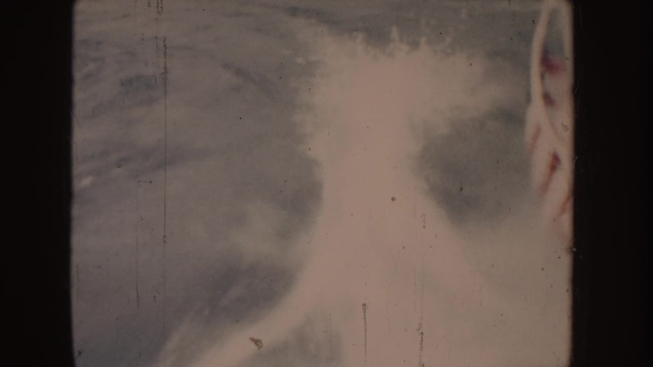 1955 Idaho 8mm frame showing pale boat spray and water texture, partly obscured by dark vertical edge shadows.