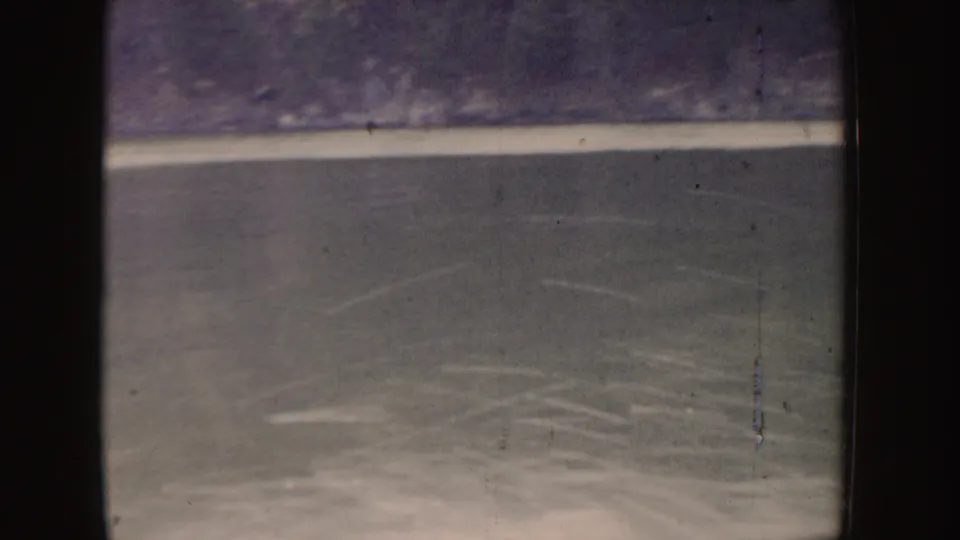 1955 Idaho 8mm frame showing rippled lake water, faint boat wake, muted color, and visible film gate edges.