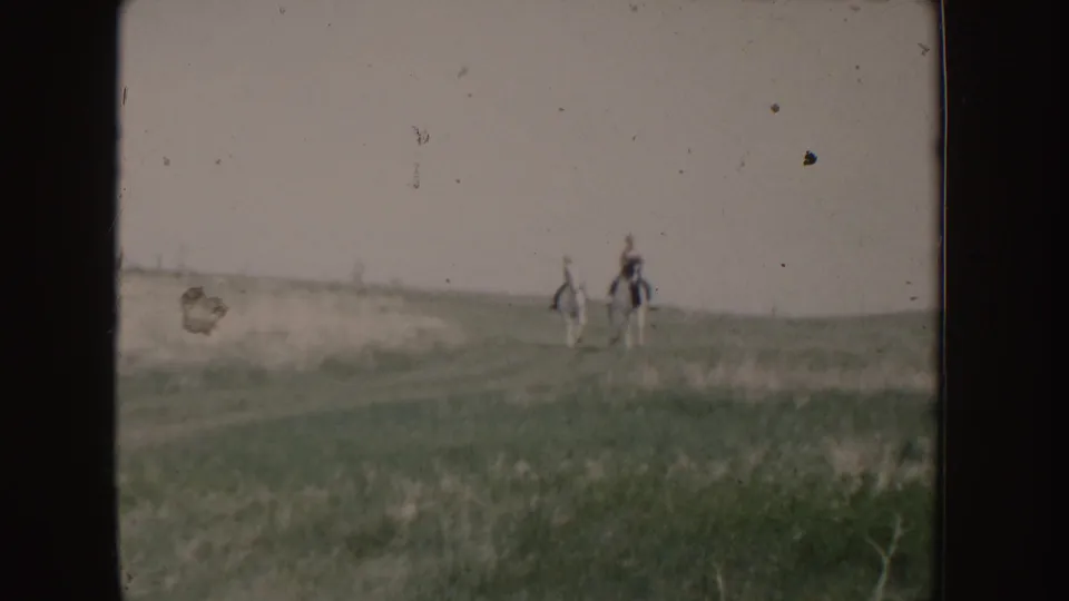 Two horseback riders appear closer in the 1955 Idaho field scene, with muted greens, soft focus, and visible film wear.