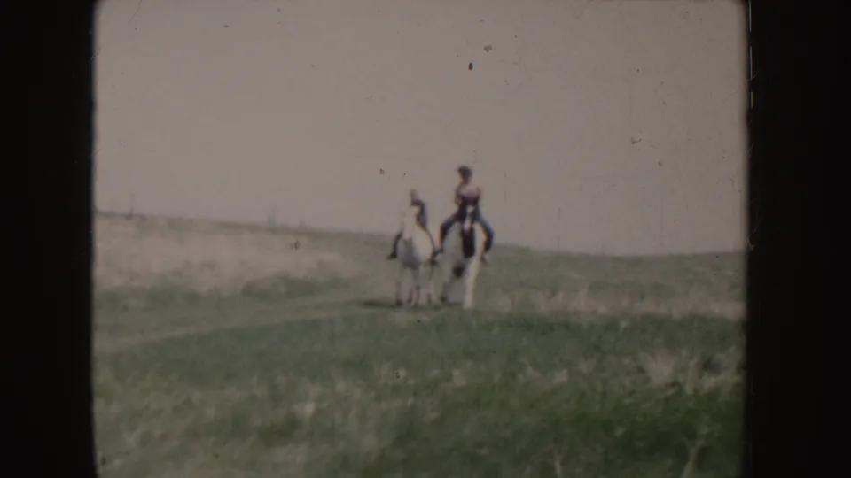 The riders and horses are nearest to the camera in this Idaho home-movie frame, still partially softened by motion and film grain.