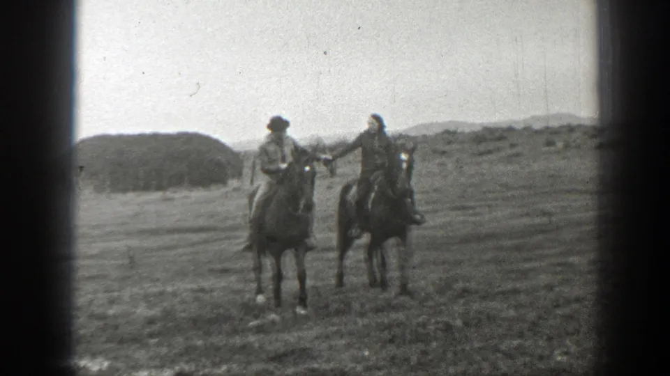 A man and woman ride close together on horses in a 1939 Montana home-movie frame.