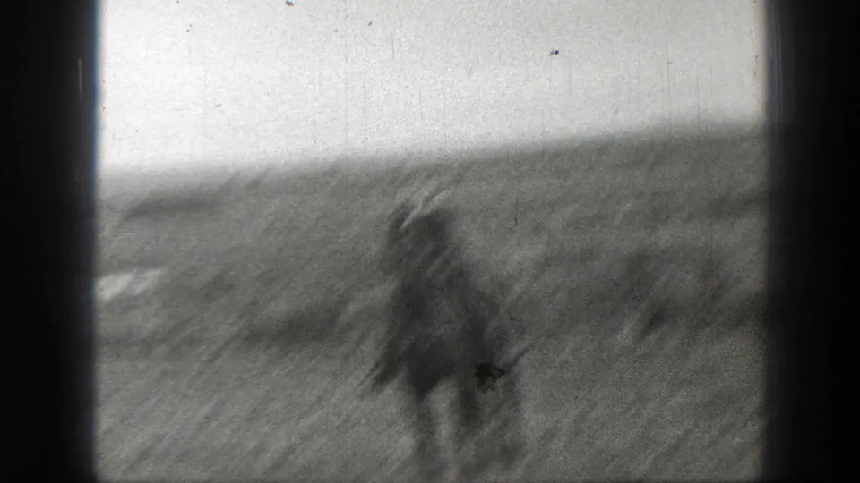 A motion-blurred rider on horseback crosses the Montana grassland, with handheld movement and dark gate borders emphasizing the home-movie scan.