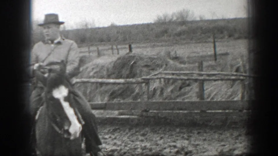 A closer 1939 Montana frame shows the mounted man in a hat and jacket beside a wooden ranch fence and muddy ground.