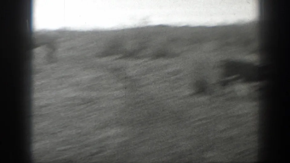 Soft black-and-white 8mm view of an open Montana field with low hills and heavy frame-edge vignetting.