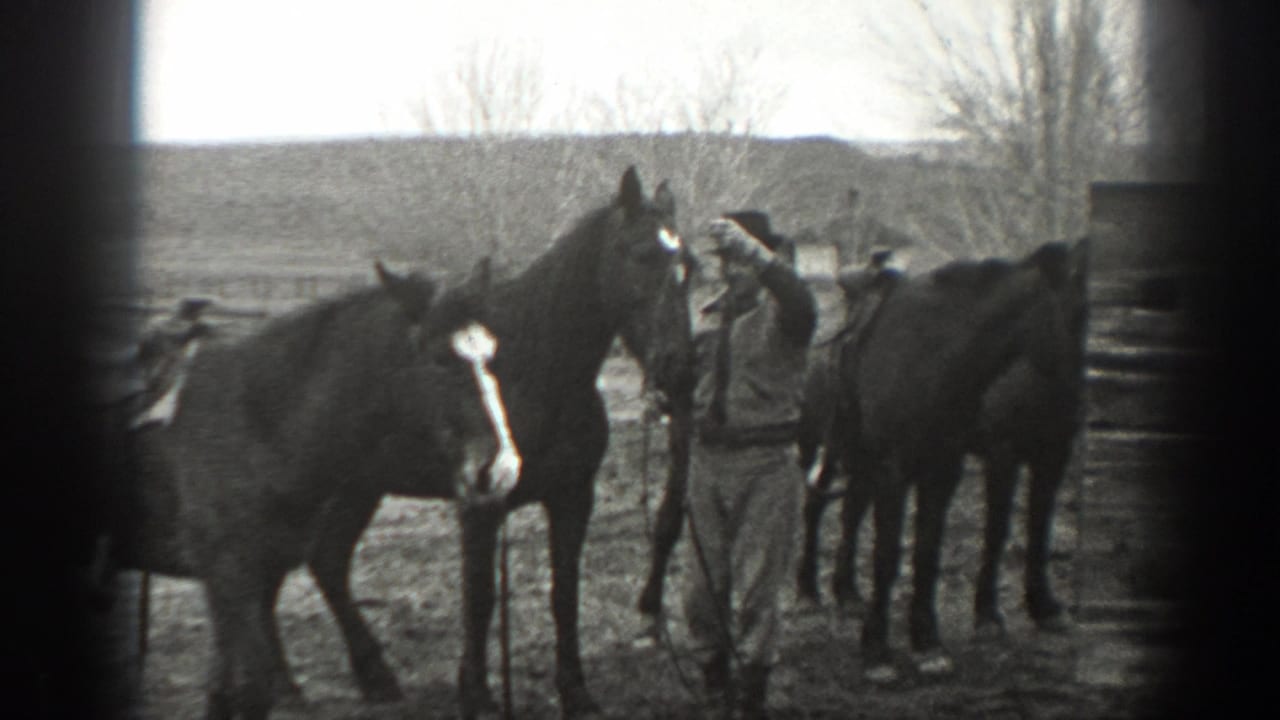In 1939 Montana home-movie footage, a man in work clothes stands close to horses in a rural paddock.