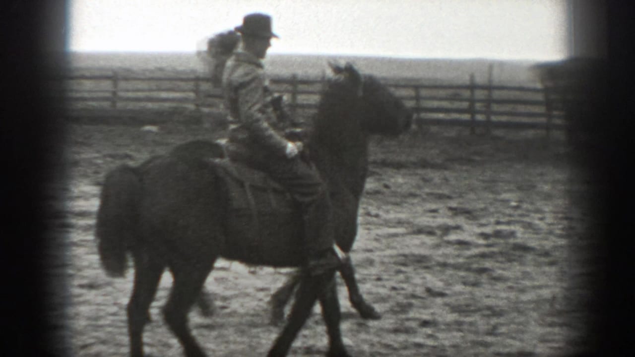 Mounted adult man in a hat and jacket rides past a rail fence in rural Montana, 1939.