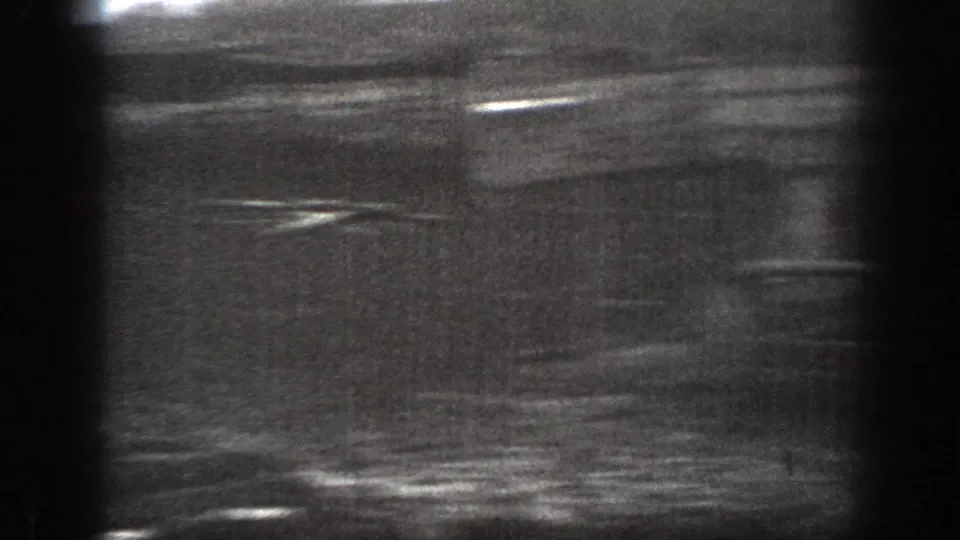 Soft, high-contrast 1939 Montana 8mm frame showing a blurred pasture area with horizontal light streaks and strong film grain.