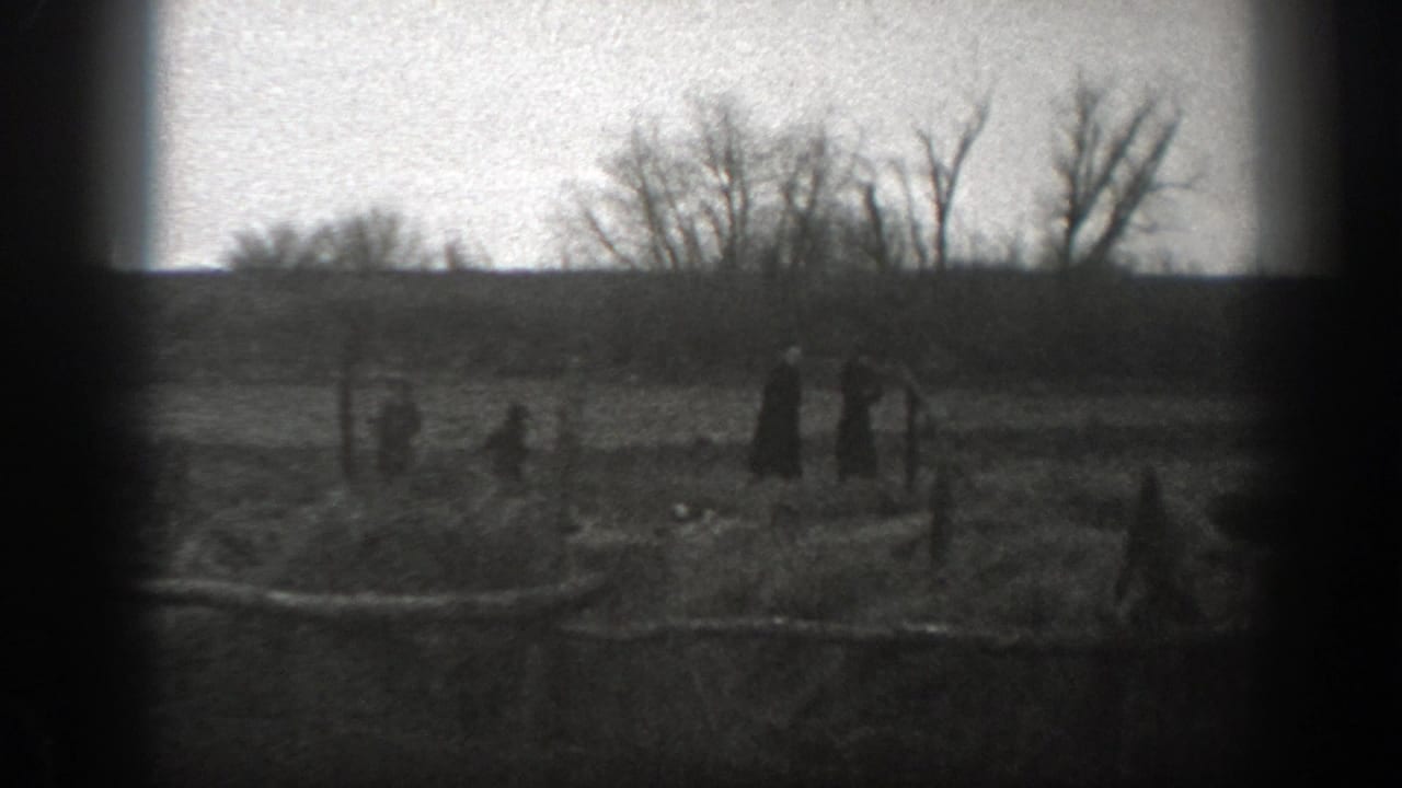 Several people walk across a fenced pasture with bare trees in the background.