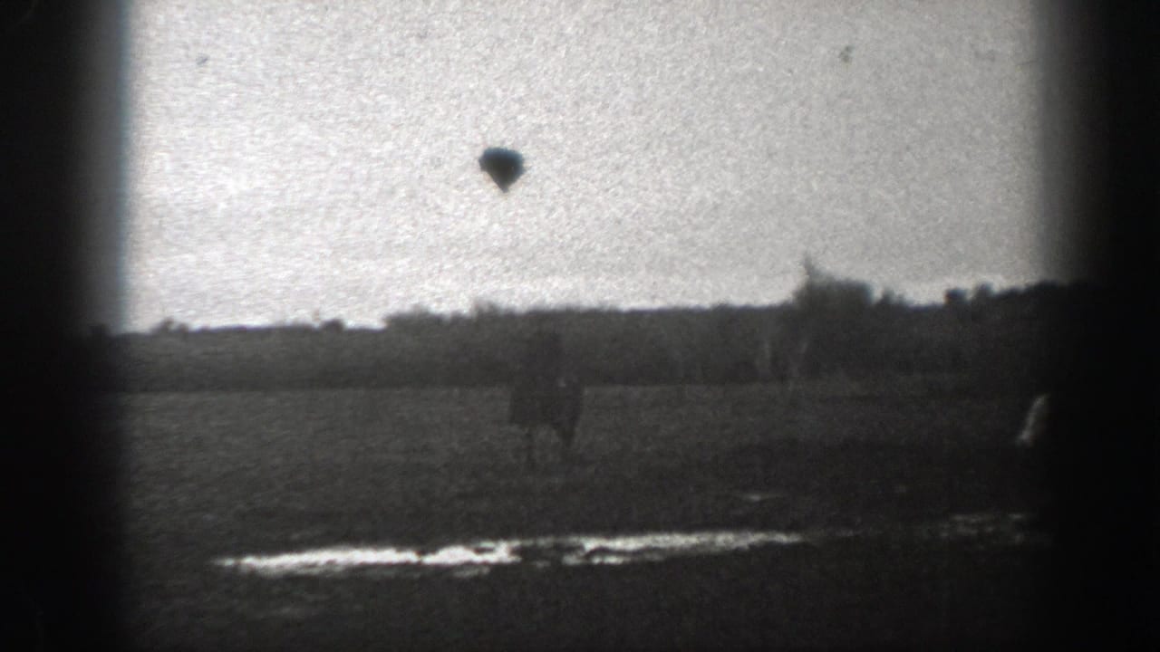 1939 Montana 8mm frame with a distant horseback rider moving across an open field, with treeline and heavy film-edge vignetting.