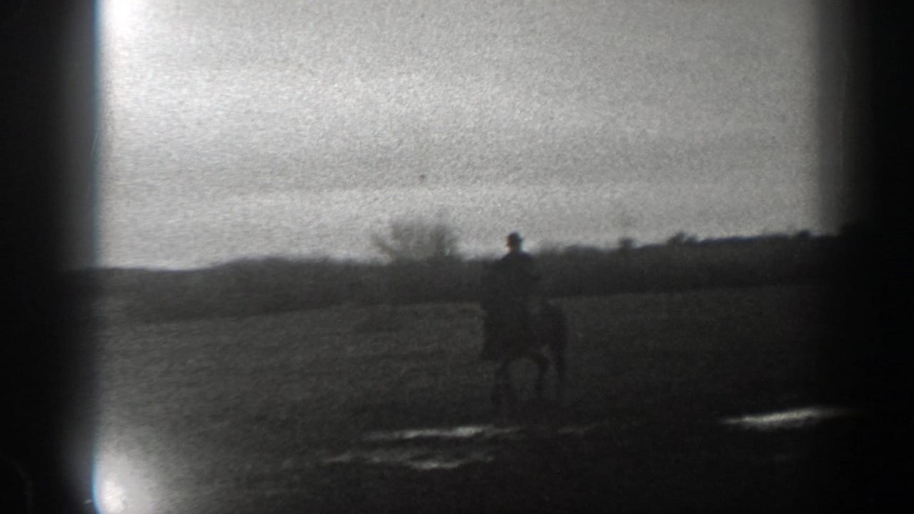 1939 Montana 8mm frame with a lone rider and horse at right, open ground in front, and a distant rural horizon behind.