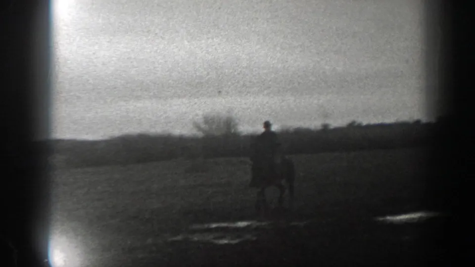 1939 Montana 8mm frame with a lone rider and horse at right, open ground in front, and a distant rural horizon behind.