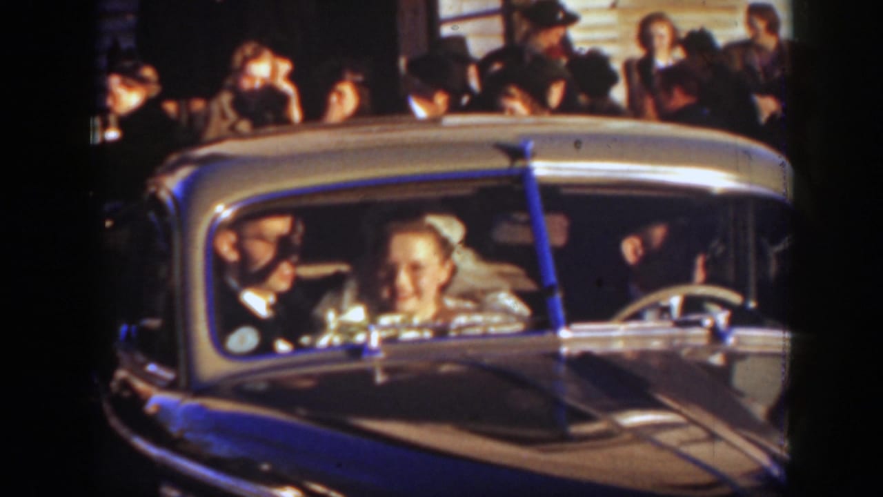 Near the end of the 1939 Montana wedding clip, the bride smiles from the car as the groom and guests remain in view.
