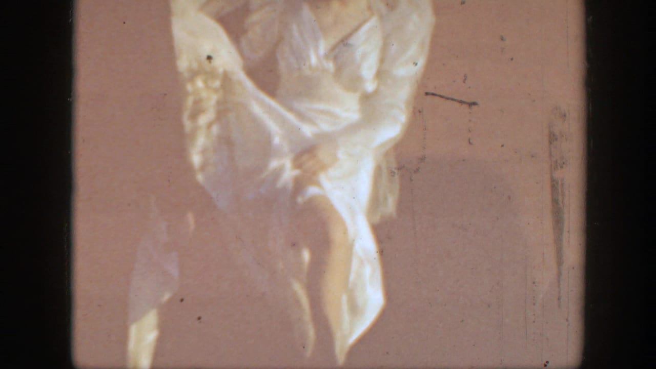 Close view of a woman in a white dress adjusting a garter on her leg.