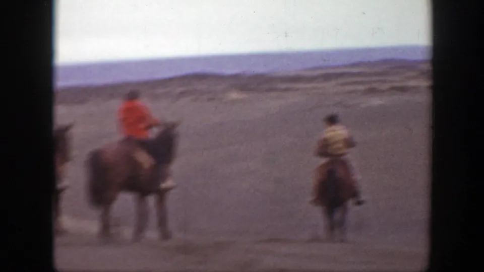 1939 Montana home-movie frame showing three mounted men moving across an arid plain under a pale sky.