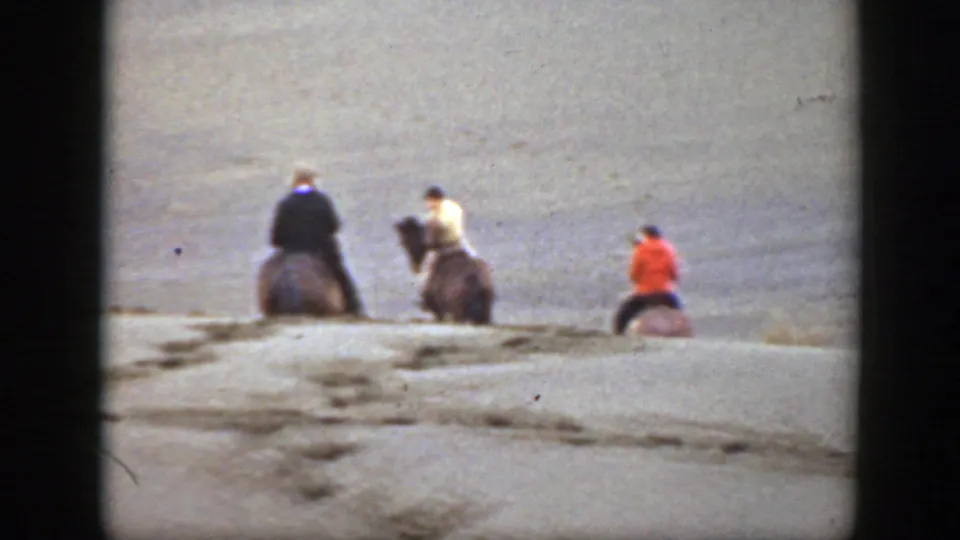 Distant 1939 Montana riders on horseback travel away from the camera across a dry, rolling plain.