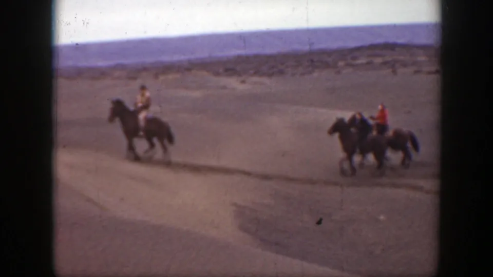 1939 Montana 8mm frame of three riders on horseback in a sandy open landscape, one wearing a bright red shirt.
