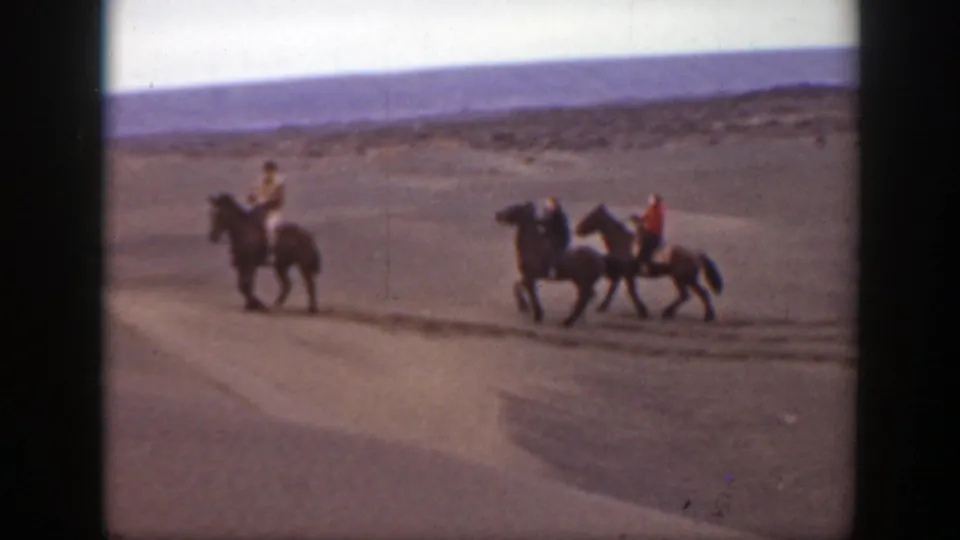 Three horseback riders traverse a sandy open landscape in archival 8mm footage identified as Montana, 1939.