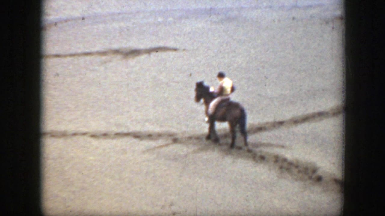 1939 Montana 8mm frame showing a distant horseback rider moving across sun-bleached open ground with visible track lines.