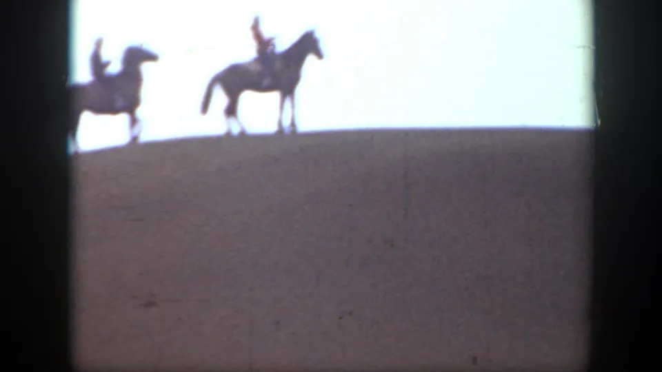 Two horseback riders are silhouetted on a low ridge against a bright sky in the 1939 Montana home-movie footage.