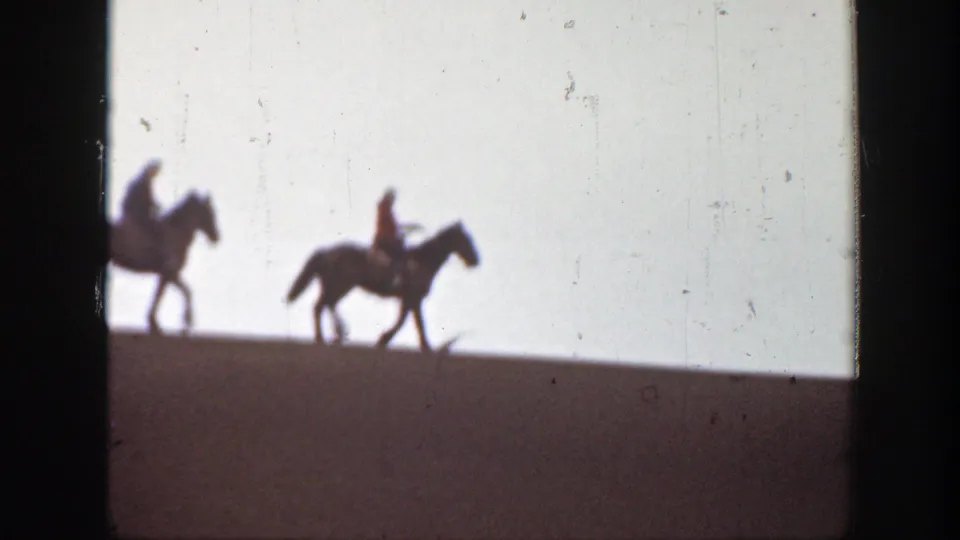 One horseback rider is partly cropped at the left edge while another crosses the ridge in Montana 1939 home-movie footage.