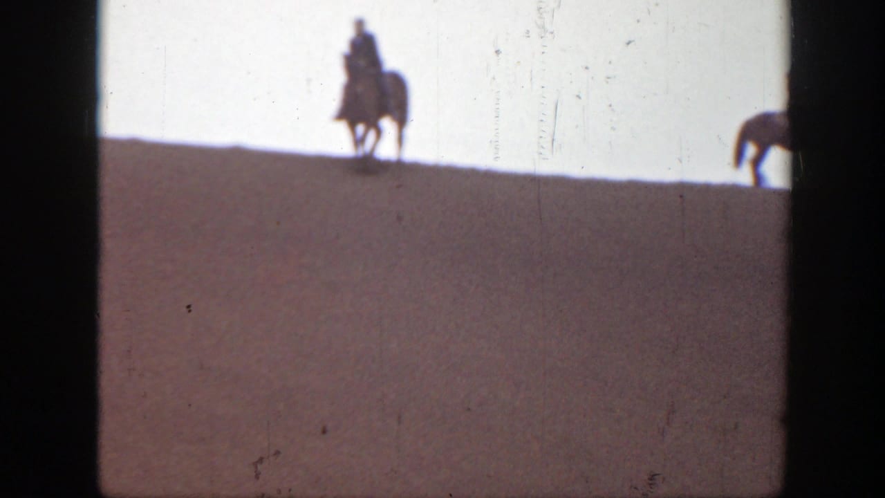1939 Montana 8mm frame showing a distant mounted rider silhouetted along a sandy ridge beneath bright overcast light.