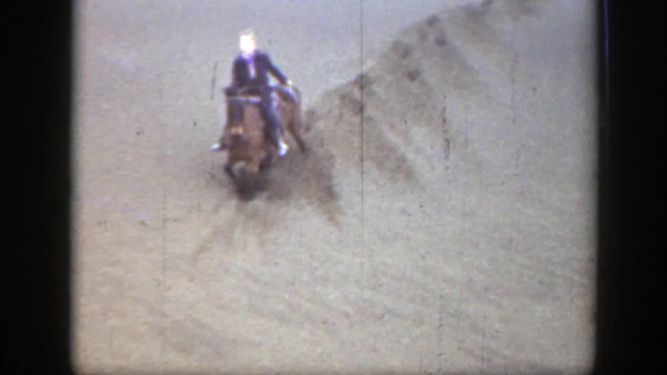 Front-facing view of a rider on horseback moving through sandy Montana terrain in a faded 1939 8mm home-movie frame.