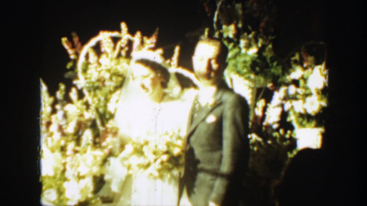 Bride and groom standing before bright floral wedding arrangements.