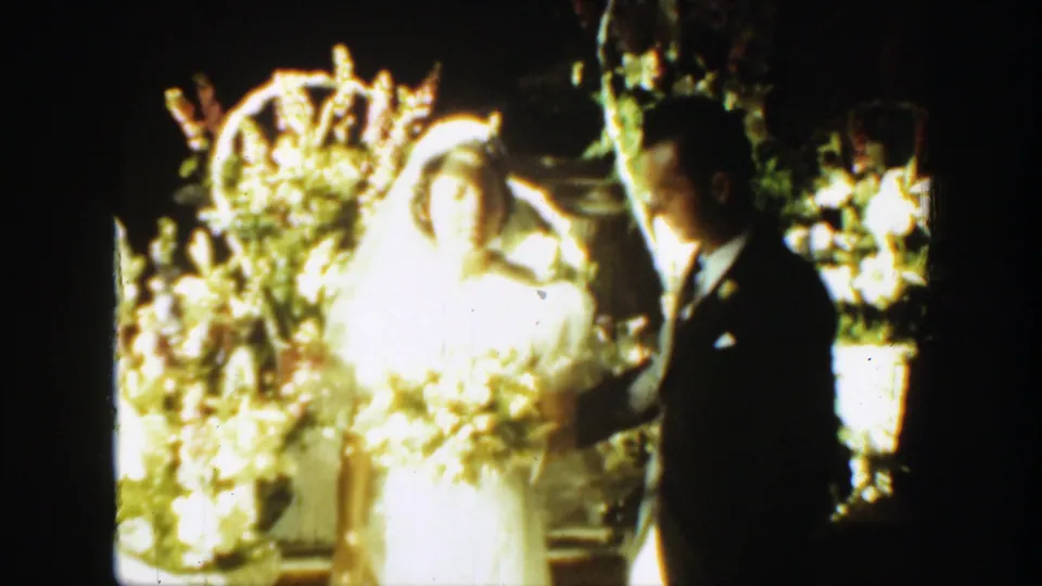 Bride in a white veil faces the groom during a Montana wedding ceremony, surrounded by flowers.