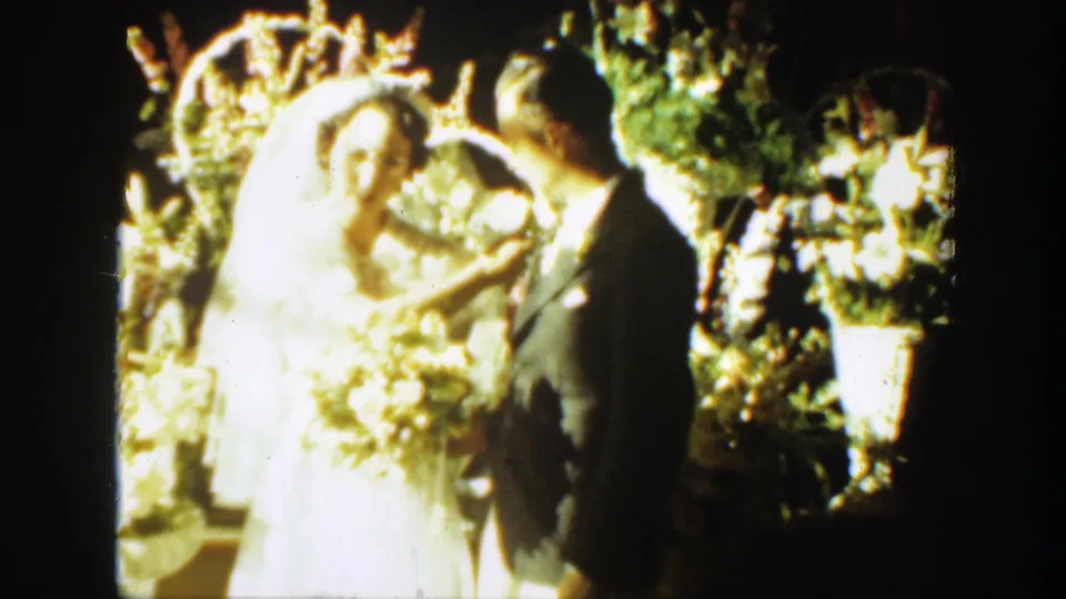 Bride with bouquet and groom in dark suit turn toward each other during the Montana wedding scene.