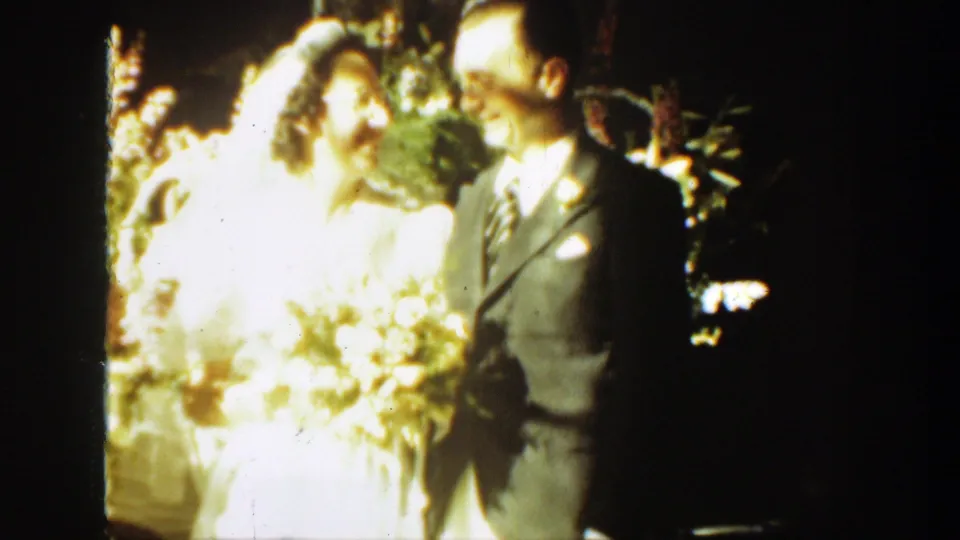 The bride and groom look toward each other near the floral arrangement in a brief 1939 Montana outdoor wedding moment.