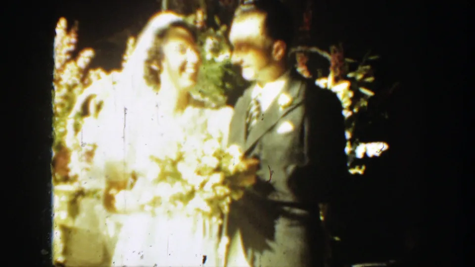 1939 Montana wedding frame showing the bride and groom close together beneath flowers in warm light.
