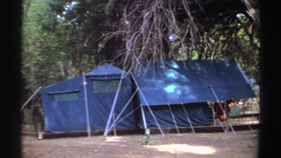 Large blue tent in a wooded Sudan camp setting, filmed in 1969 on handheld 8mm footage.